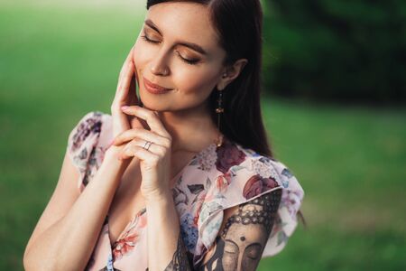 Portrait of beautiful girl in summer dress posing of greenery on backgroundの写真素材