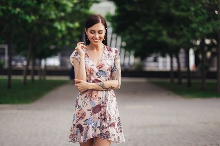 Beautiful girl in pink dress with flowers posing outdoors on summer dayの写真素材
