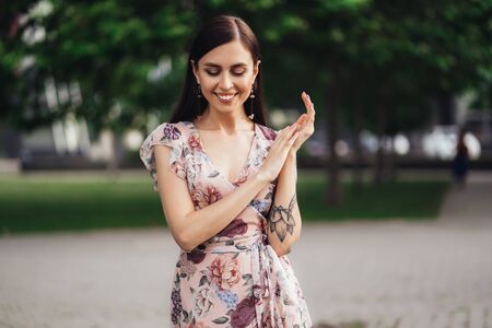 Smiling girl in dress with tattoo on her hands posing of greenery on backgroundの写真素材