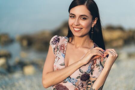 Portrait of beautiful smiling girl in summer dress posing on waterfrontの写真素材