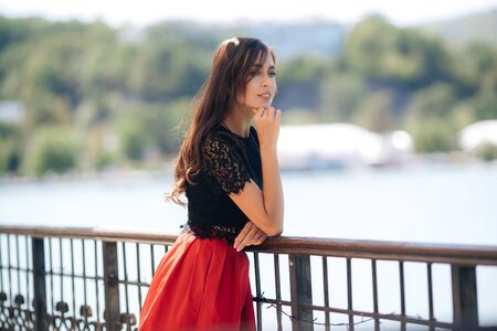 Beautiful happy girl posing outdoor wearing red skirt and black blouseの写真素材