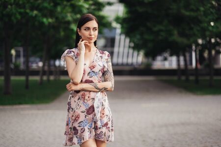Beautiful girl in pink dress with flowers posing outdoors on summer dayの写真素材