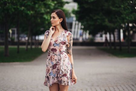 Beautiful girl in pink dress with flowers posing outdoors on summer dayの写真素材