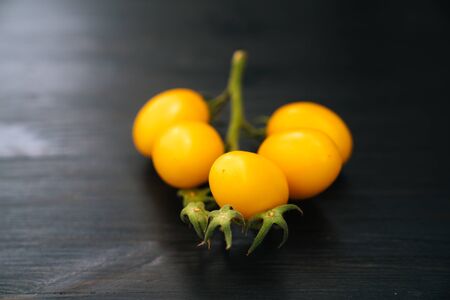 Top view of yellow cherry tomatoes on black wooden backgroundの写真素材
