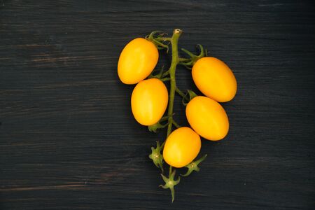 Top view, yellow cherry tomatoes in bowl on black wooden background, copy spaceの写真素材