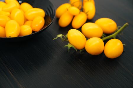 Top view, yellow cherry tomatoes in bowl on black wooden background, copy spaceの写真素材
