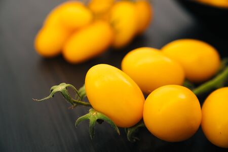 Top view of yellow cherry tomatoes on black wooden backgroundの写真素材