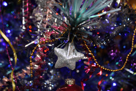 White Ð¡hristmas toy star on the background of a Christmas tree decorated with blue and red...