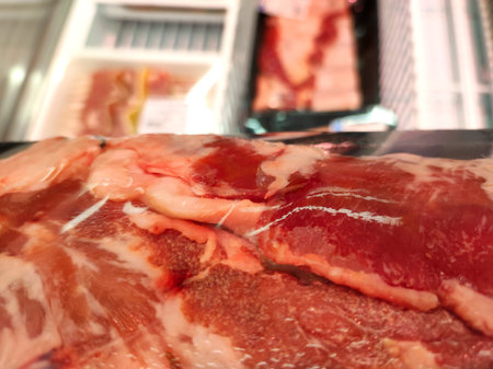 Packaged cut of fresh raw red meat in a supermarket on the background of a refrigerator with meatの写真素材