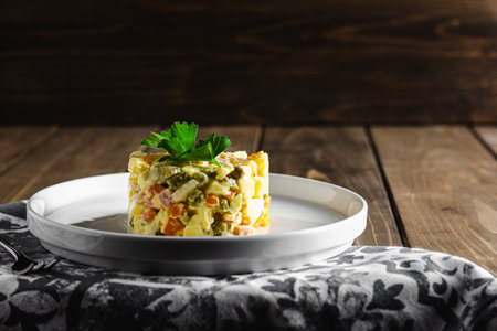 Traditional russian salad Olivier from boiled vegetables and sausage with mayonnaise in bowl. Russian New Year or Christmas salad on wooden background with copy space.の写真素材