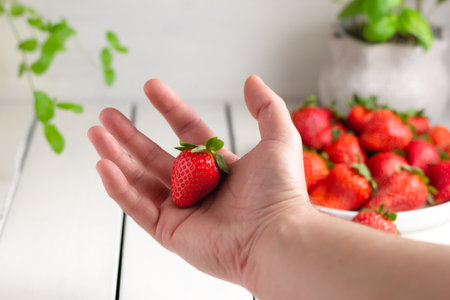 Hand holding a strawberry isolated on white background. close up.の写真素材