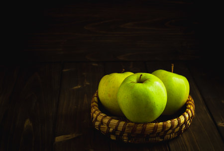 Green organic healthy apples in bowl on wooden board. Healthy food dark backgroundの写真素材