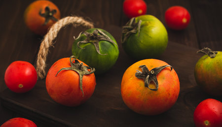 Collection of whole colored tomatoes served on a wooden rustic background, tomatoes still lifeの写真素材