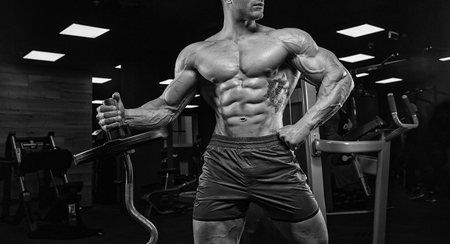 Handsome man with big muscles, posing at the camera in the gymの写真素材
