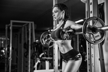 fitness girl exercising with barbell in gymの写真素材
