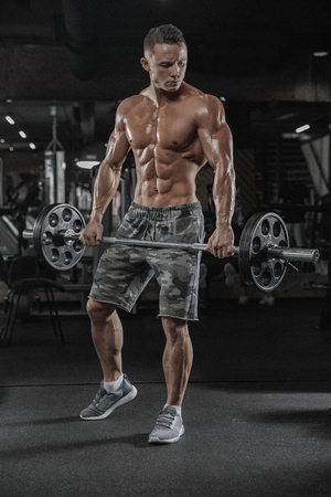 Handsome man with big muscles, posing at the camera in the gymの写真素材