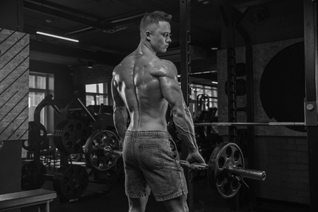 Handsome man with big muscles, posing at the camera in the gymの写真素材