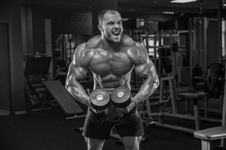 Bodybuilder man lying exercisers squeezing large dumbbells.の写真素材
