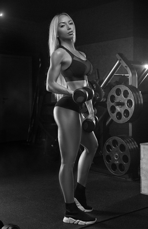 Fitness woman posing in the gym. Perfect physique athletic young woman with six pack, perfect abs, shoulders and biceps. Crossfit womanの写真素材