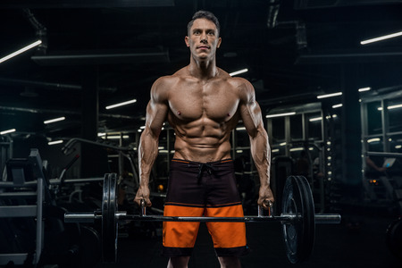 Attractive tall muscular bodybuilder doing heavy deadlifts in moder fitness center.の写真素材