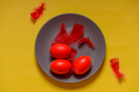 Colorful traditional painted Easter eggs. Red eggs, yellow background. Three eggs in a gray plateの写真素材