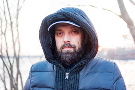 Headshot of a man in a hood. Man in a gray jacket with a hood. A man with a beard.の写真素材