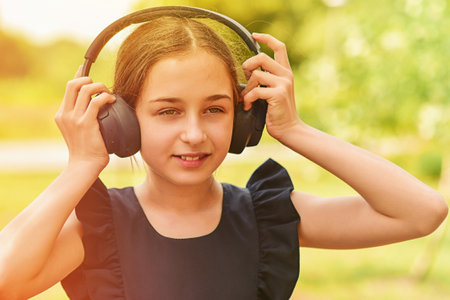 Happy little girl wearing headphones. Stereo sound.の写真素材