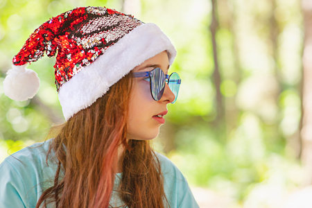 Beautiful little girl with long hair wearing a Santa Claus hat in Christmas.