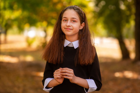 Little girl 11 or 12 years old in a dress on the background of nature in autumn. School concept.