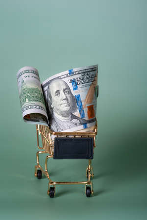 Shopping, discounts. American banknotes dollars in a shopping cart on a light green background.の写真素材