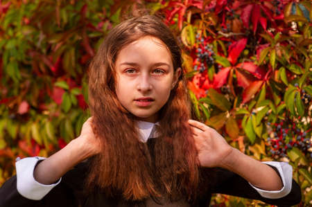 Schoolgirl portrait. A girl straightens her curly hair in nature.の写真素材