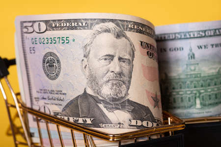 Shopping, discounts. American banknotes dollars in a shopping cart on a yellow background.の写真素材
