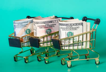 Financial and banks concept. Three shopping baskets with dollars in them on a turquoise background.の写真素材