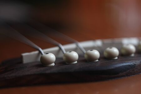 acoustic guitar brown bridge,white saddle and strings, blurry backgroundの写真素材