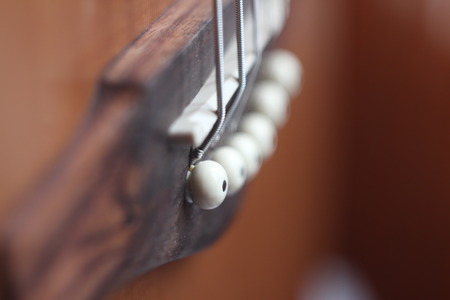 acoustic guitar brown bridge, white saddle and strings, with side view and blurry backgroundの写真素材