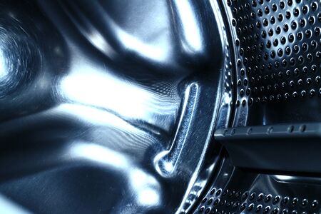 washing machine with an empty stainless steel drum with blue tint, metal parts for design and backgroundの写真素材