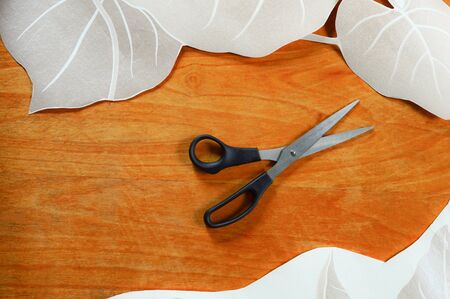 scissors on a wooden table, paper with decorative elements for interior design of an apartment, top viewの写真素材