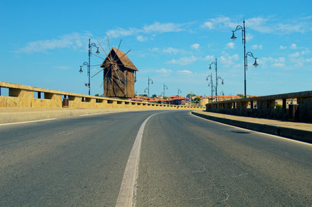 low angle view of the road to the old town of Nessebar with a windmill on a sunny bright day