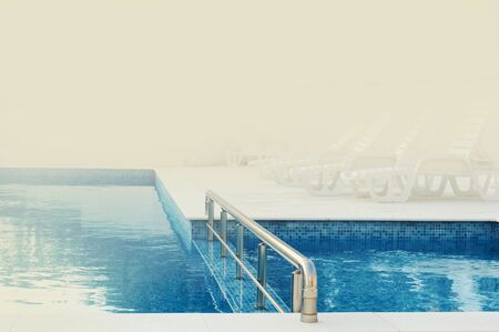 swimming pool with blue water ready to use in the foggy summer morning, with space for textの写真素材