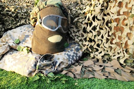 military uniforms with face shield mask, balaclava and glasses, against camouflage netting backgroundの写真素材
