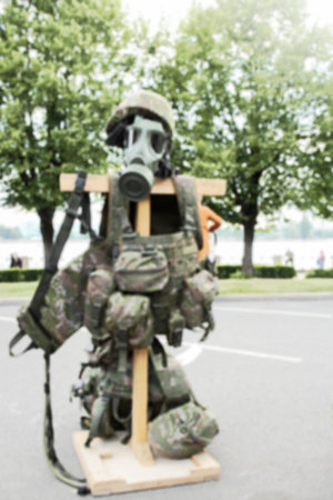 Blurred for the design of the text, military uniform with a gas mask and a helmet on a wooden cross...