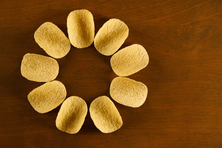 sun or flower shaped potato chips on a wooden table, top view with copy space for text and design...
