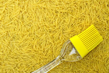 background with italian pasta vermicelli and yellow silicone kitchen brush or tassel with transparent handle, copy space for text and design elementsの写真素材