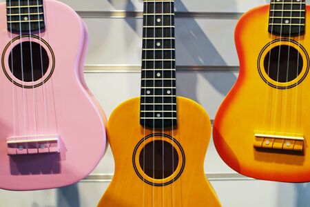 pink, brown and yellow ukulele guitar in the shop on the background of the wallの写真素材