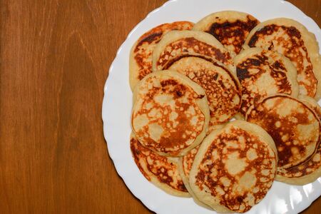 homemade toasted sweet pancakes on a white dish on a wooden table with copy space, top viewの写真素材