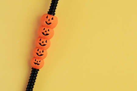 one black decorative cocktail straw with orange happy pumpkin smiley faces on yellow background, Halloween drinks menu design for cocktail party, copy space for textの写真素材