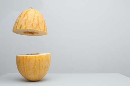 Fresh ripe melon halves flying in the air, fruit levitation concept, healthy natural vegetarian organic food, copy space for textの写真素材