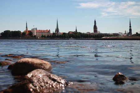 Riga Old Town on the other side of the Daugava River with blurred stones in front on a bright summer...