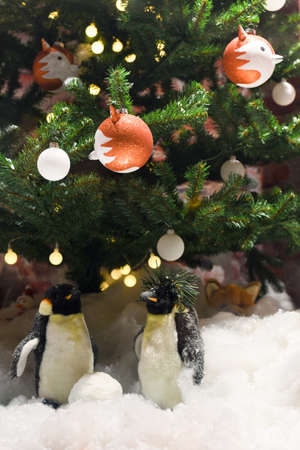 two penguins in the snow and a Christmas tree with a garland and decoration, New Year celebration compositionの写真素材
