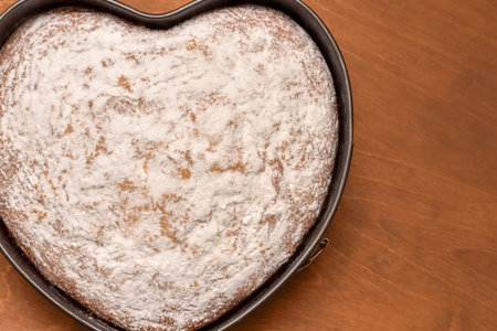 heart shaped cake in springform pan, freshly baked and dusted with powdered sugar